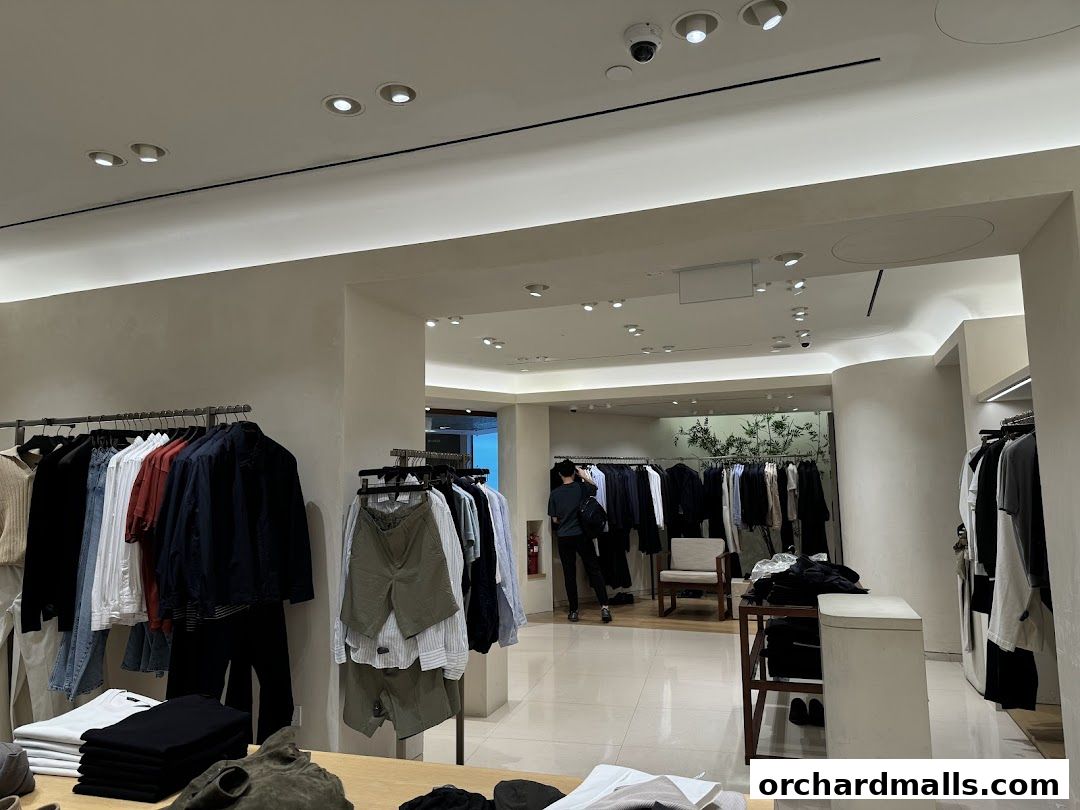 Interior view of a clothing store with racks of men's apparel and a customer browsing.