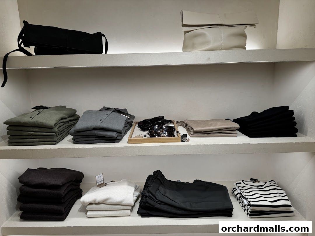 Neatly folded clothing and accessories displayed on shelves in a retail store.