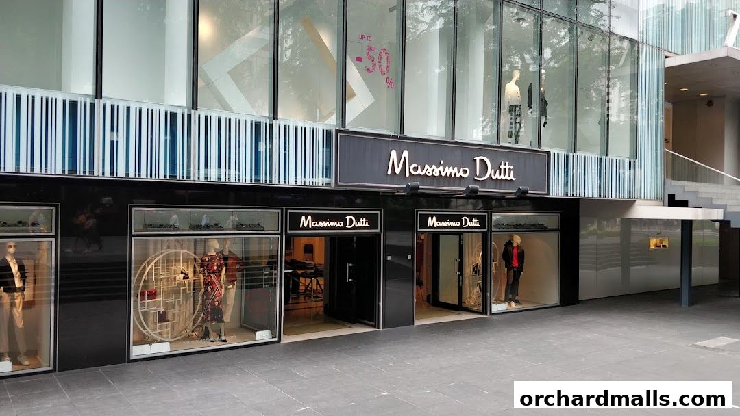 The exterior of a Massimo Dutti store with mannequins in the windows and a sale sign.