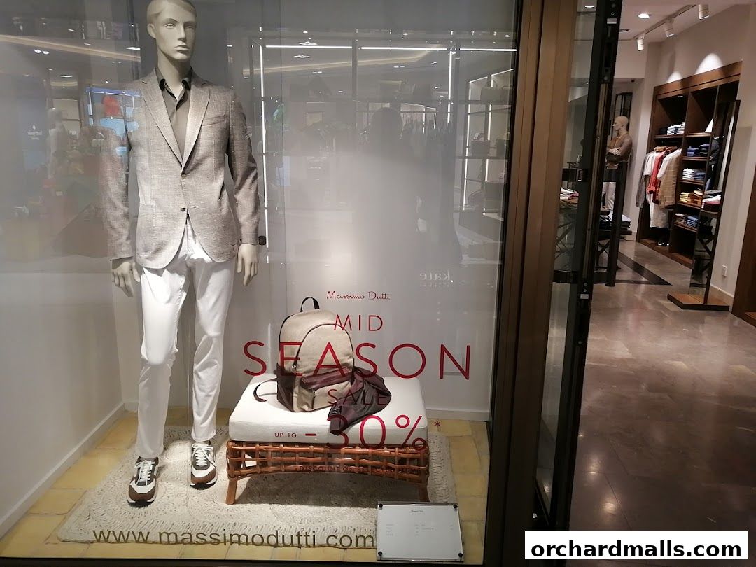 Mannequin in a suit displayed in a Massimo Dutti shop window with a mid-season sale.