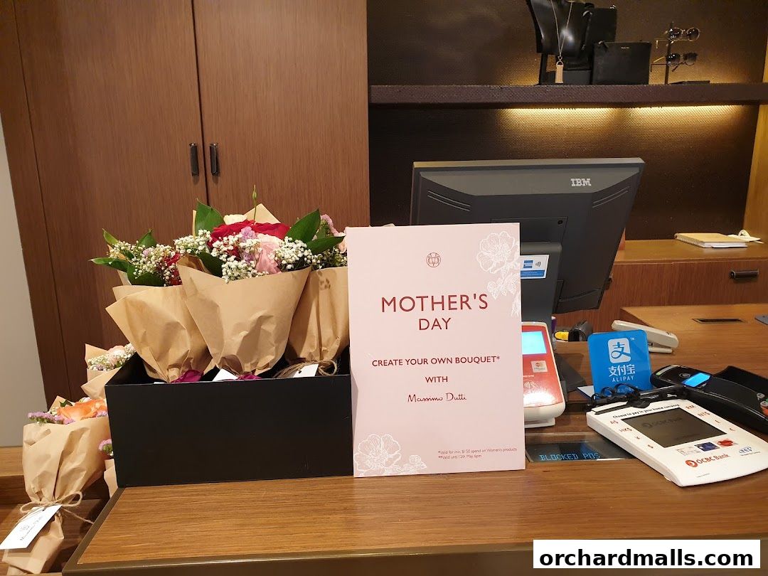 Massimo Dutti shop counter with Mother's Day bouquets and payment terminals.