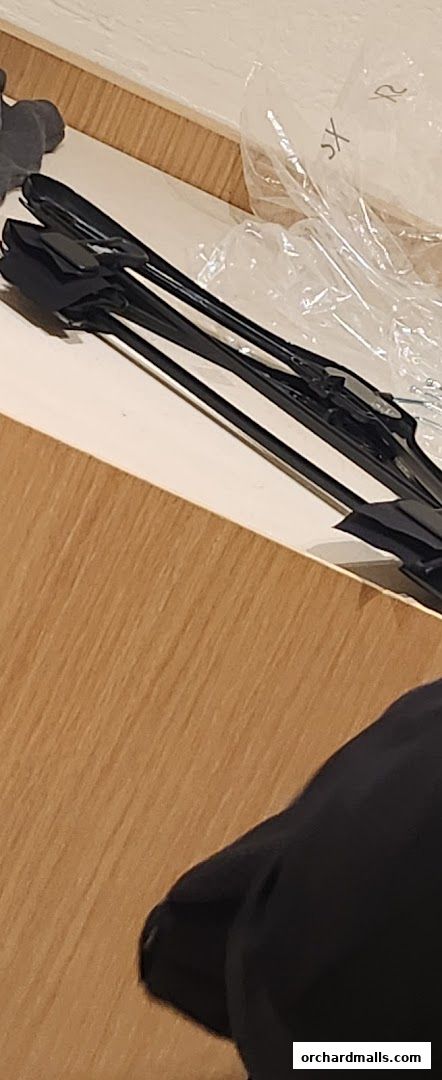 A close-up shot of black hangers and plastic-wrapped items on a wooden surface.