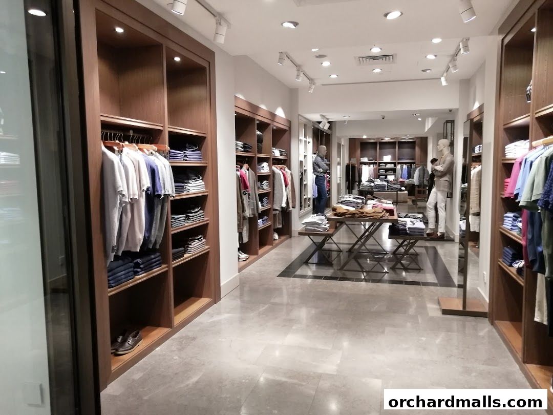 Interior view of a well-lit men's clothing store with apparel displayed on shelves and racks.