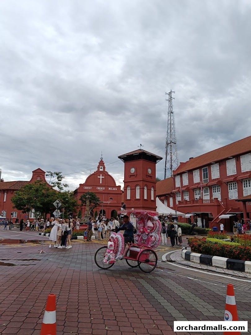 A pink decorated trishaw is parked in front of the Christ Church Melaka.