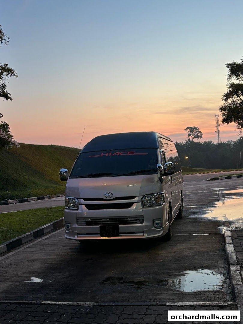 A silver Toyota Hiace van parked outdoors during a sunset.