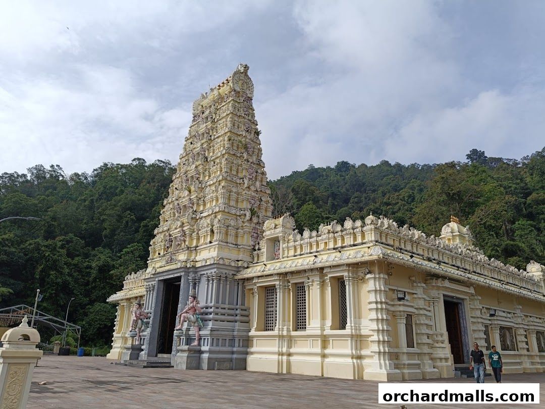 A grand Hindu temple with intricate architecture set against a lush green forest backdrop.