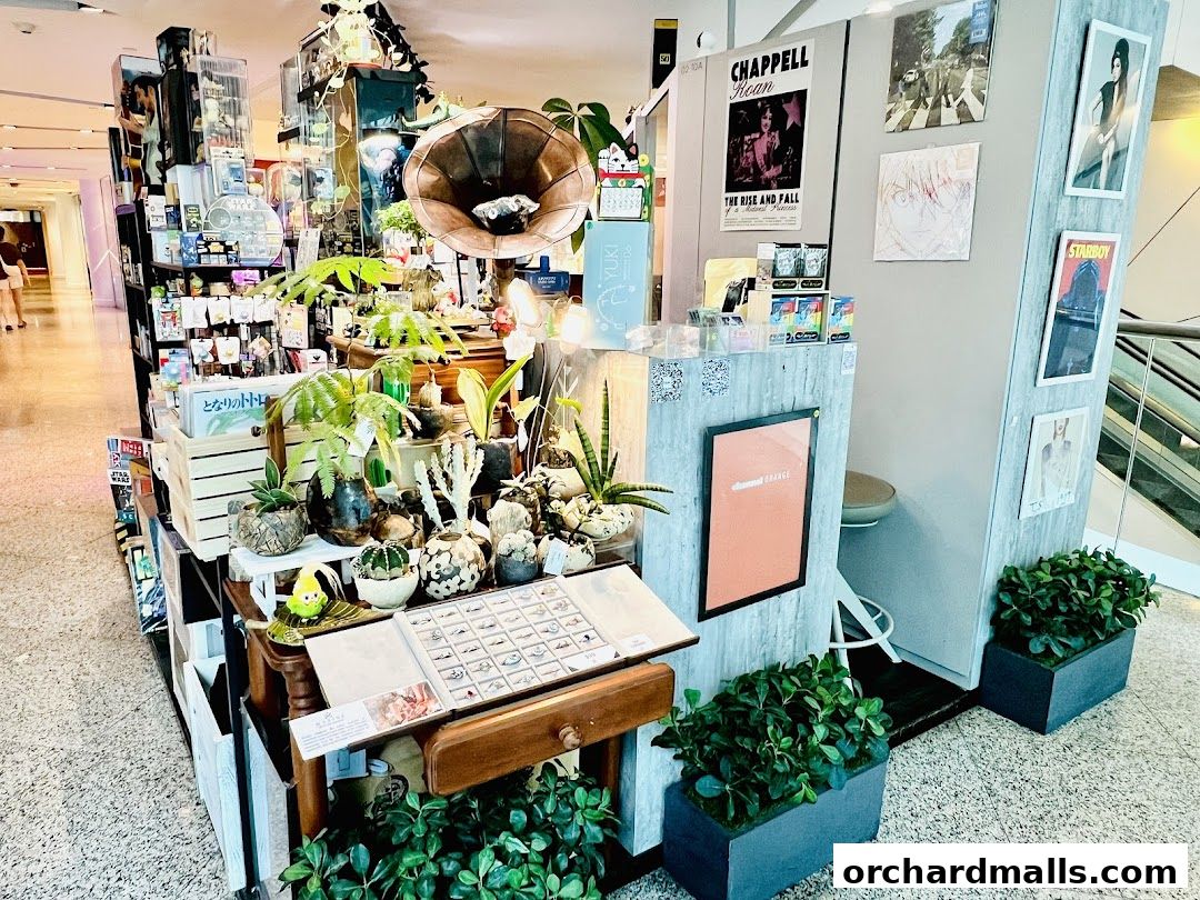 A retail display featuring plants, decorative items, and artwork in a shopping mall.