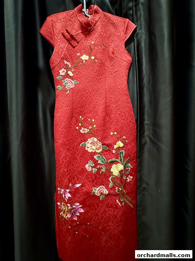 A red cheongsam dress with intricate floral embroidery and a textured pattern.