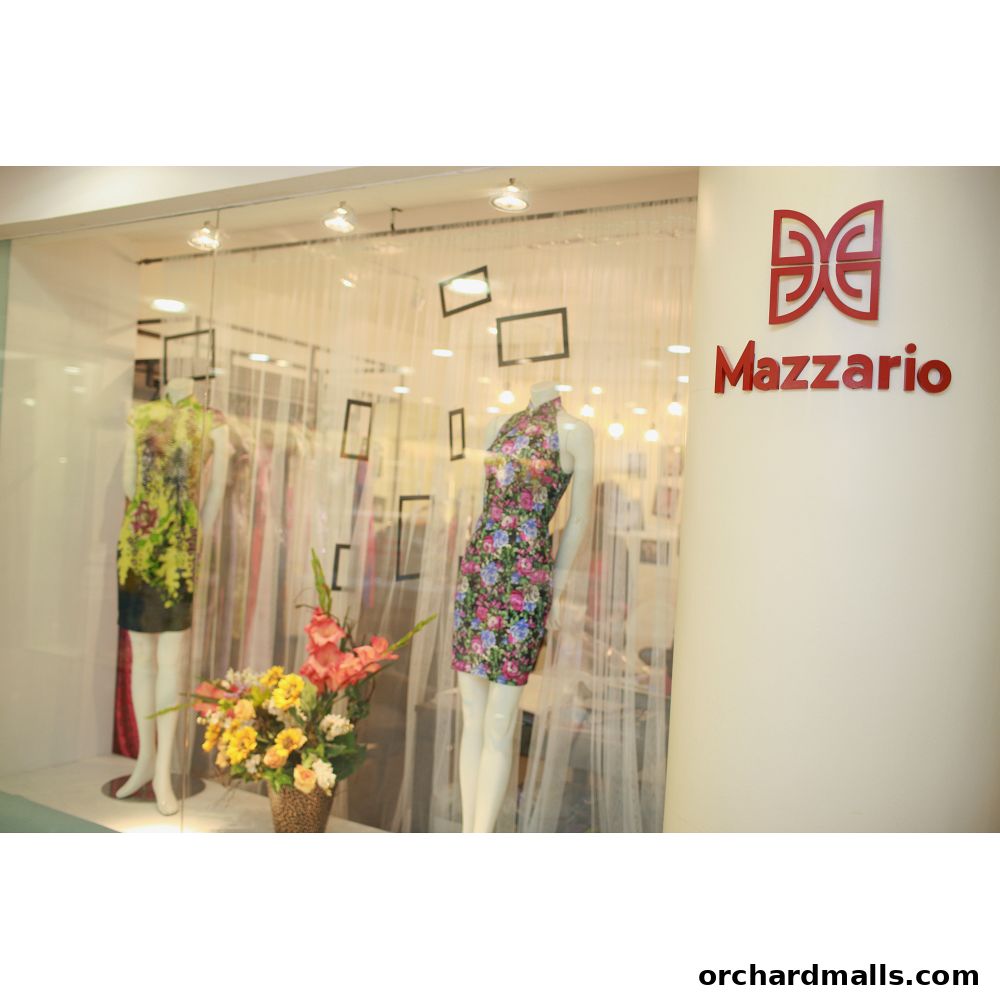 Mazzario shop window display featuring mannequins in floral dresses and a flower arrangement.