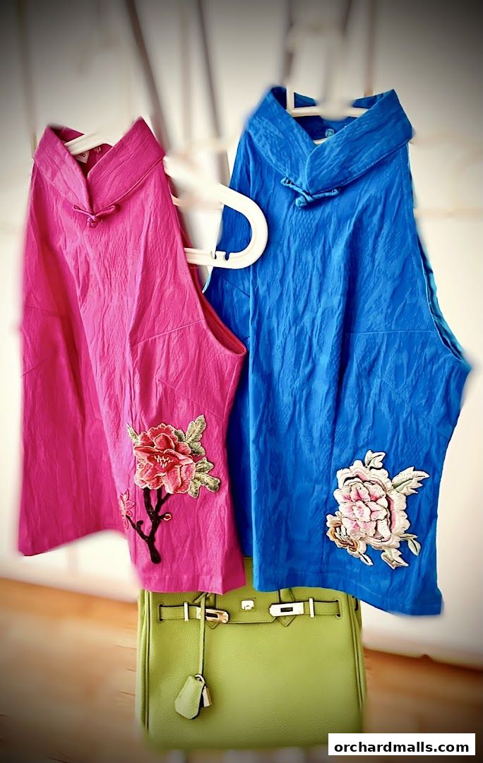 Two embroidered tops, pink and blue, displayed with a lime green handbag.