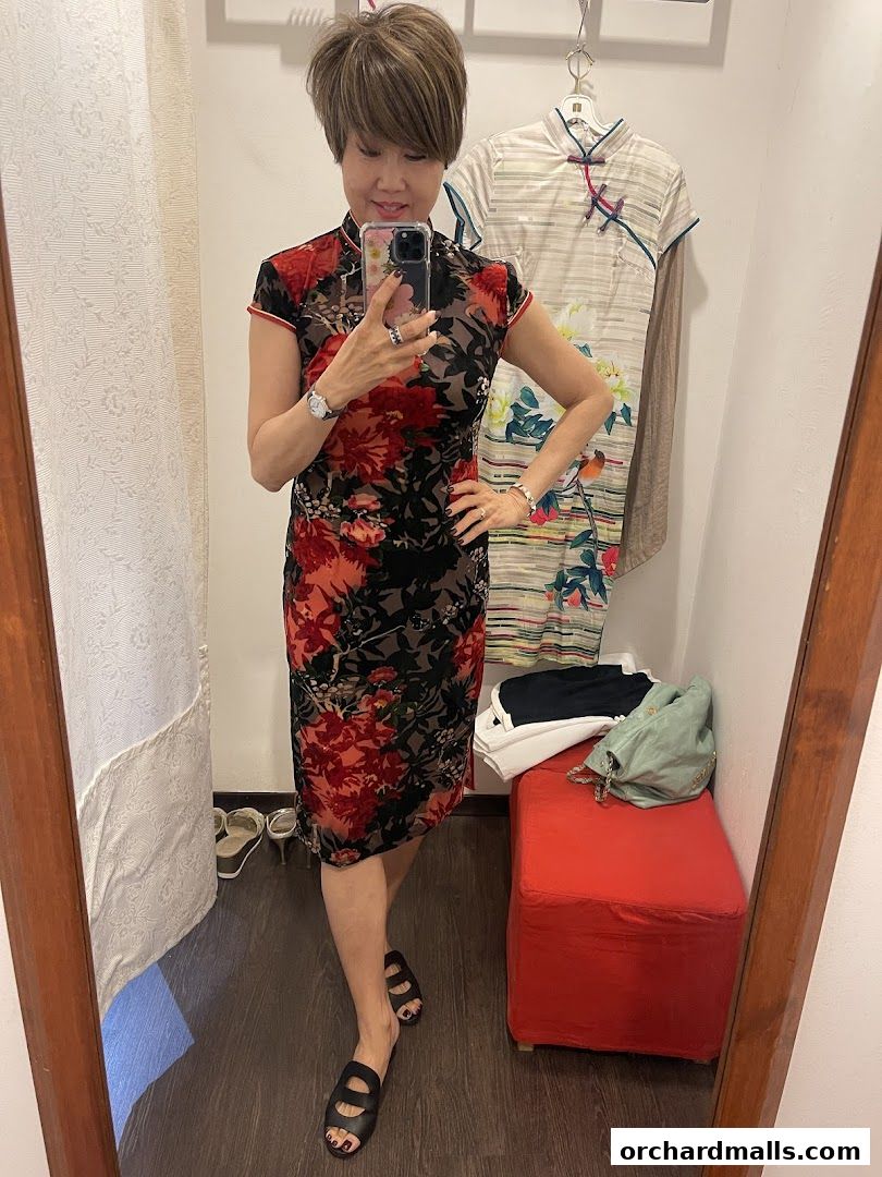 A woman tries on a floral dress in a boutique fitting room.