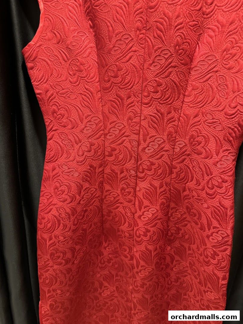 A close-up of a red dress with a textured floral pattern.