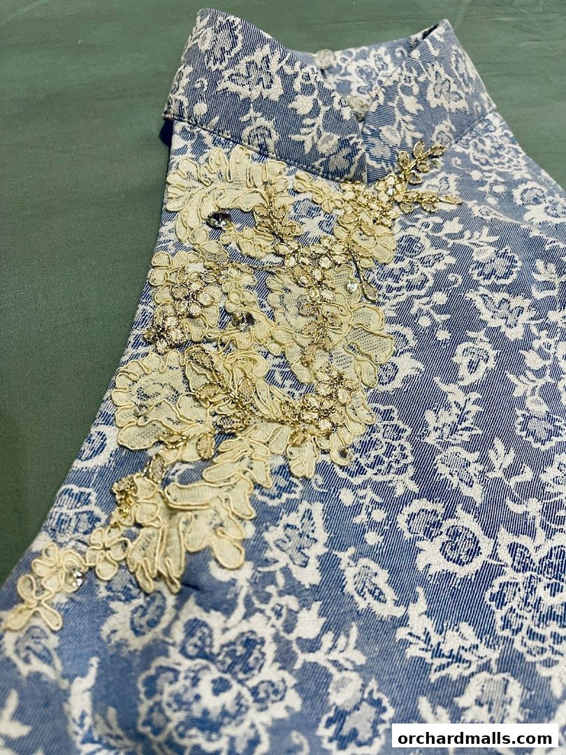 Close-up of a blue and white patterned garment with intricate lace and bead embellishments.
