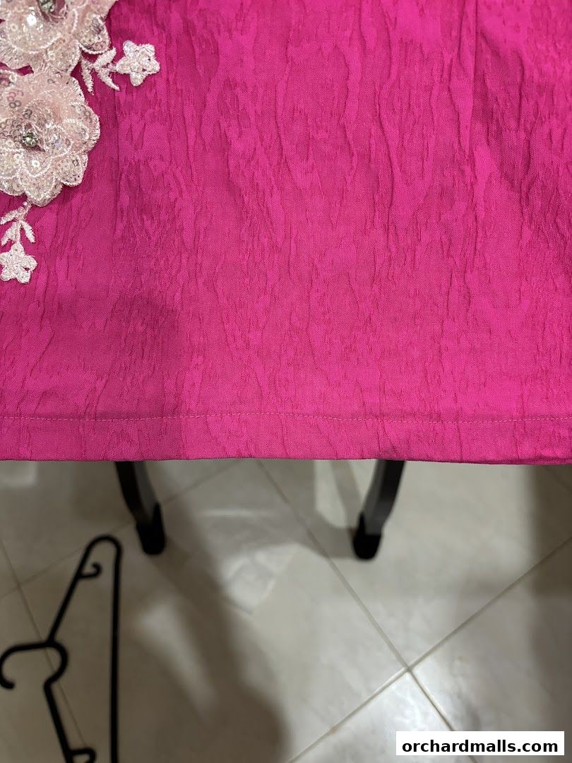 A close-up of a vibrant pink textured fabric with delicate white floral embellishments.