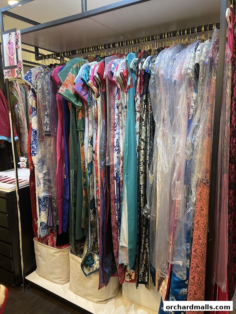 A rack of colorful traditional Chinese dresses, many in protective plastic covers.