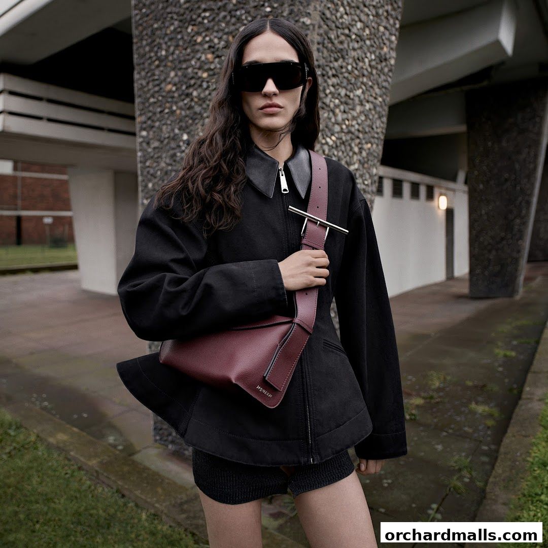 A model poses with a burgundy leather handbag and stylish sunglasses.