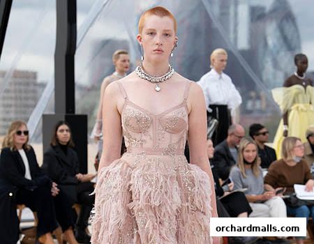 A fashion show with models wearing elaborate dresses and an audience watching.