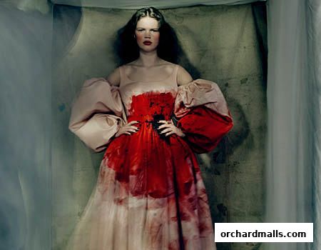 A model wears a dramatic, avant-garde gown with a red, abstract print and voluminous sleeves.