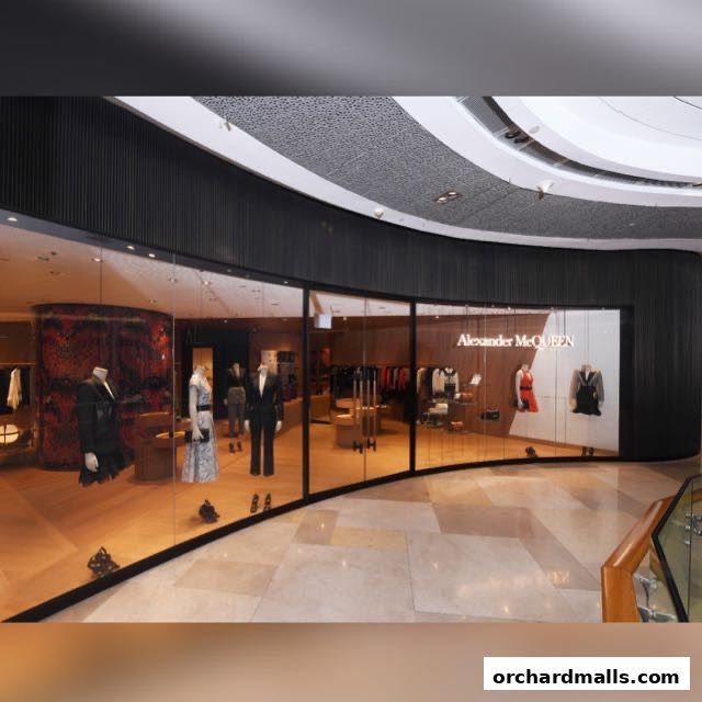 The Alexander McQueen store features a modern glass facade showcasing mannequins in stylish attire.