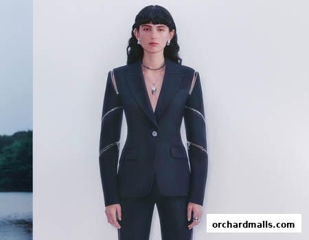 A model wears a dark blue McQueen suit with zipper details on the sleeves.