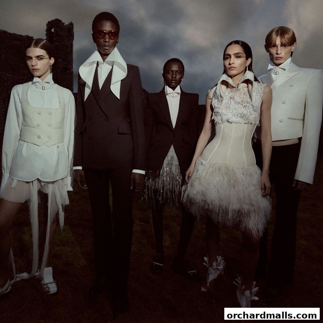 Five models in avant-garde fashion stand in a dramatic outdoor setting.