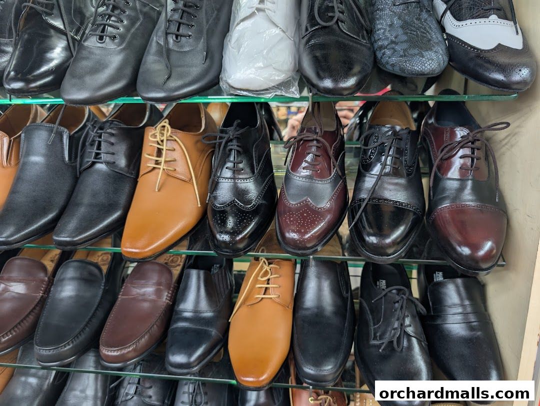 A display of various men's dress shoes on shelves, including oxfords and loafers.