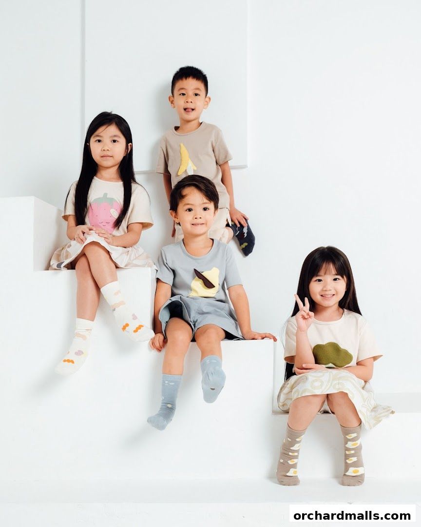 Four children in cute, playful outfits sit on white steps, showcasing children's clothing.