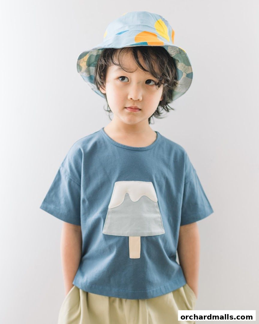 A young boy wearing a blue t-shirt with an ice cream design and a bucket hat.