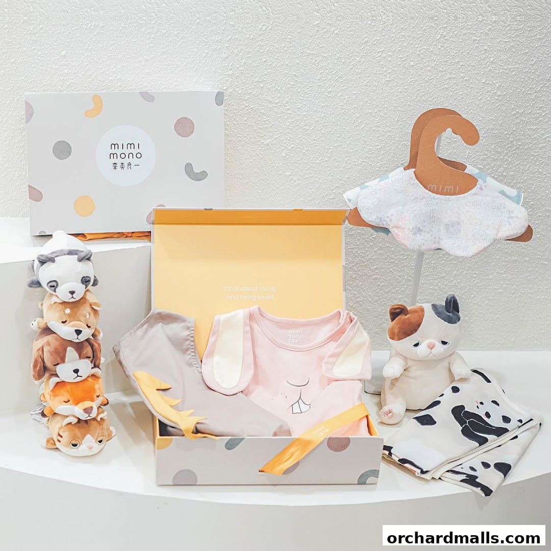 A gift set with baby clothes, plush toys, and a bib from Mimi Mono.