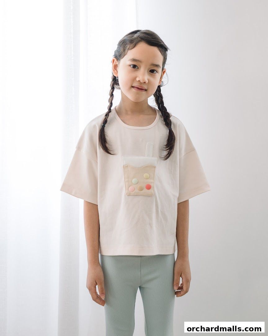 A young girl with braided hair wears a light-colored t-shirt with a bubble tea graphic.