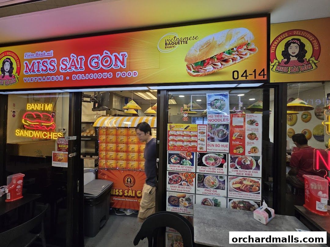 Exterior of Miss Saigon Singapore, a Vietnamese restaurant with vibrant signage and food displays.