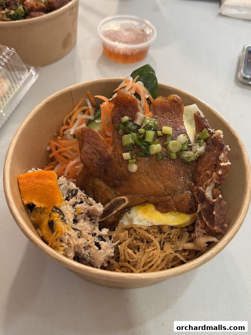 A close-up of a delicious Vietnamese rice bowl with grilled pork and various toppings.