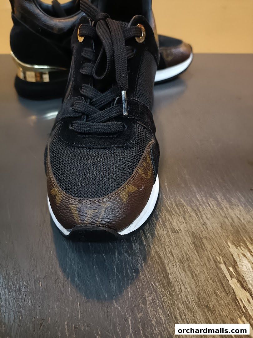 Close-up of stylish black sneakers with brown monogram accents and gold detailing.