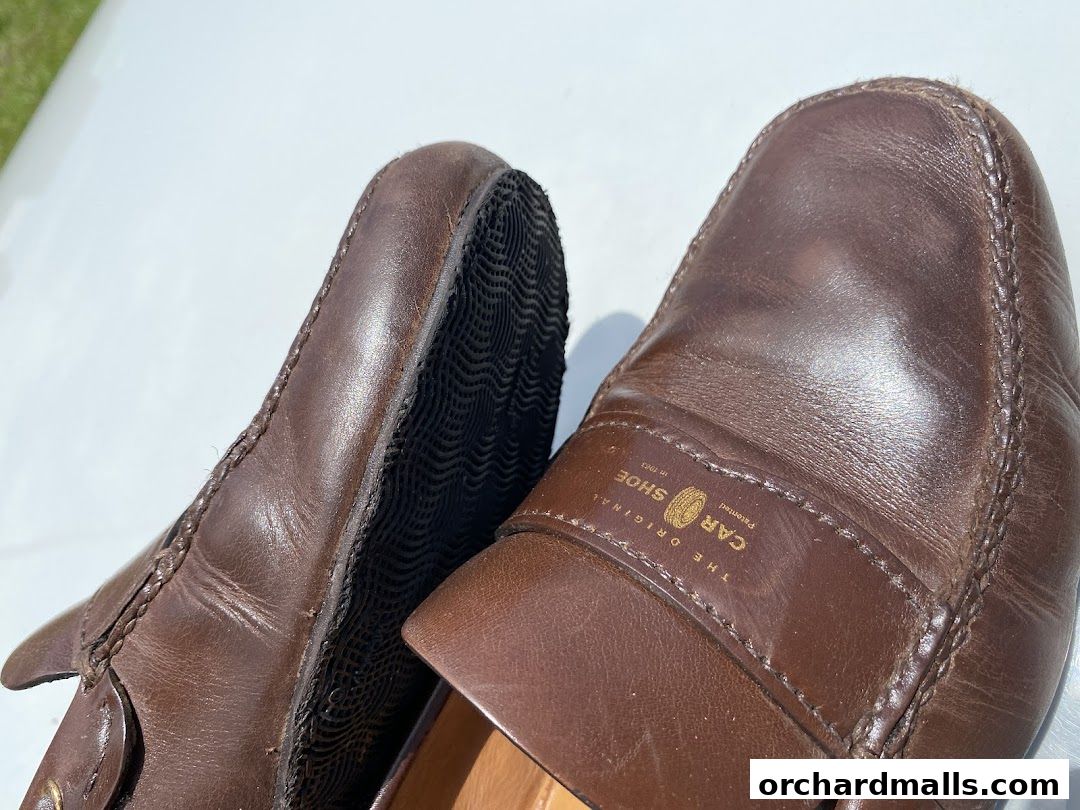 Close-up of two brown leather moccasin shoes, one showing its sole.