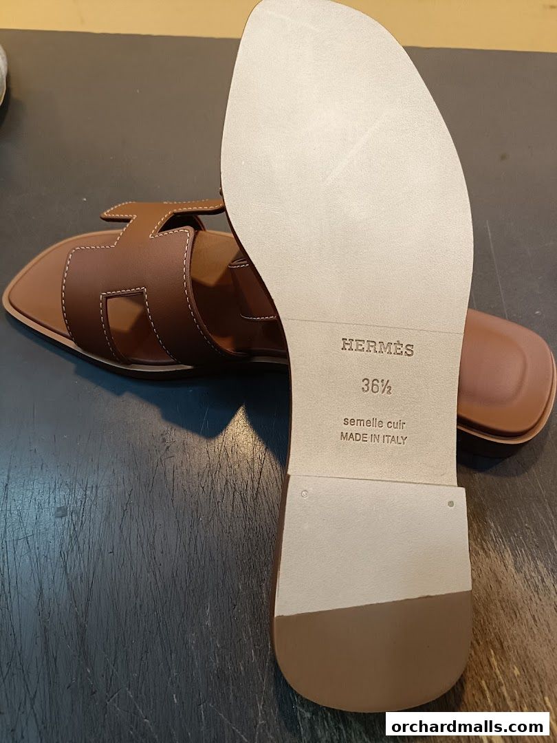 A close-up of a brown Hermes sandal with its sole showing size and origin.