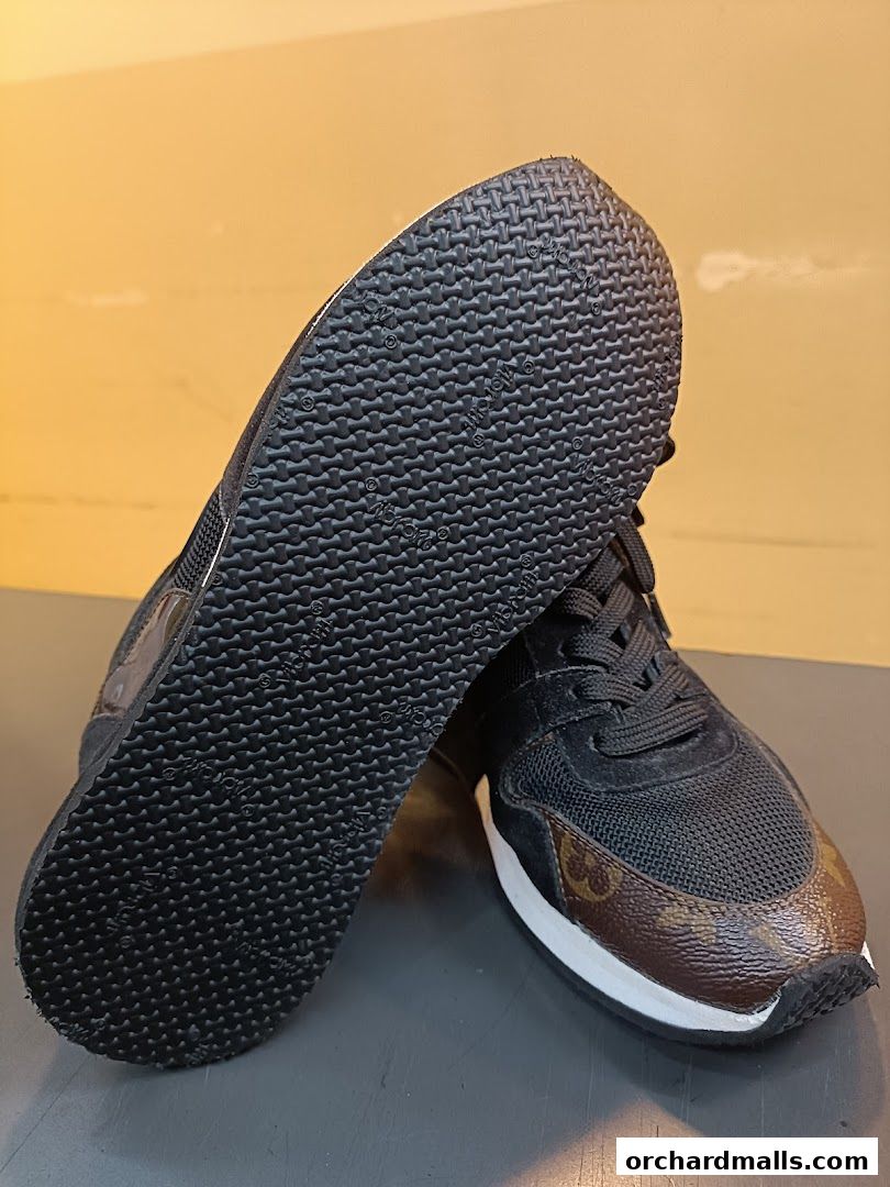 A pair of black sneakers with brown Louis Vuitton pattern accents and white soles.