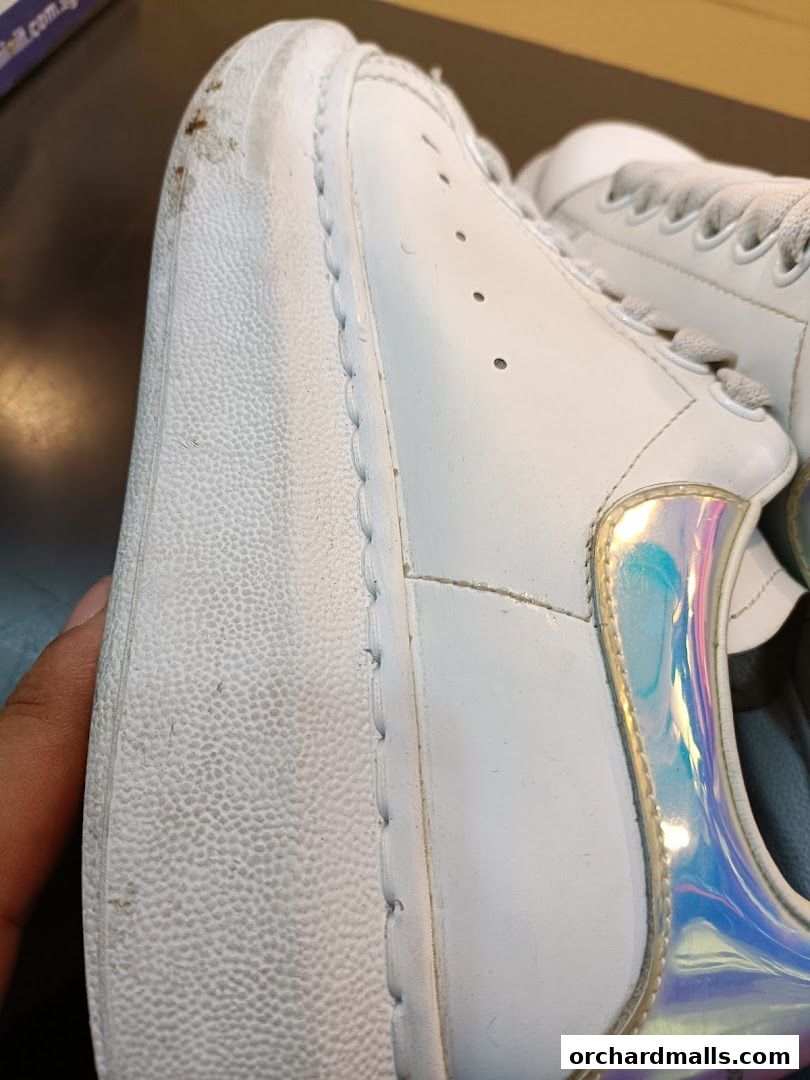 Close-up of a white sneaker with a thick sole and iridescent heel detail.