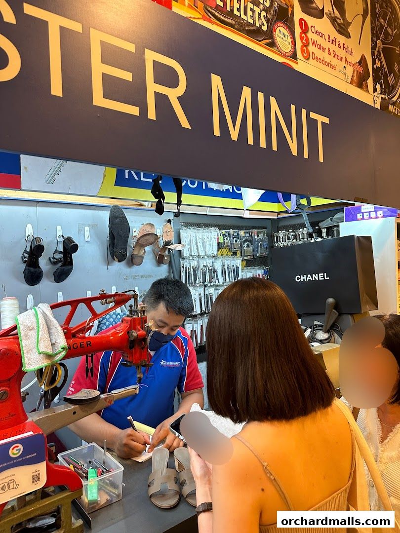 A cobbler works at Mister Minit, repairing shoes with a sewing machine.