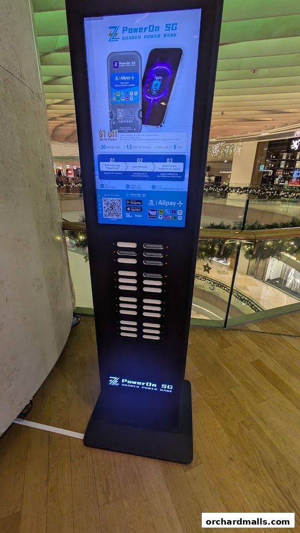 A tall, black charging station with multiple charging ports and a digital display showing a power bank.