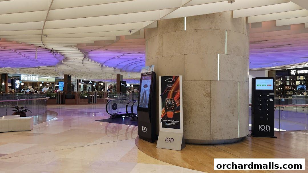 A mobile device charging station is located in a modern shopping mall with a directory and advertising displays.