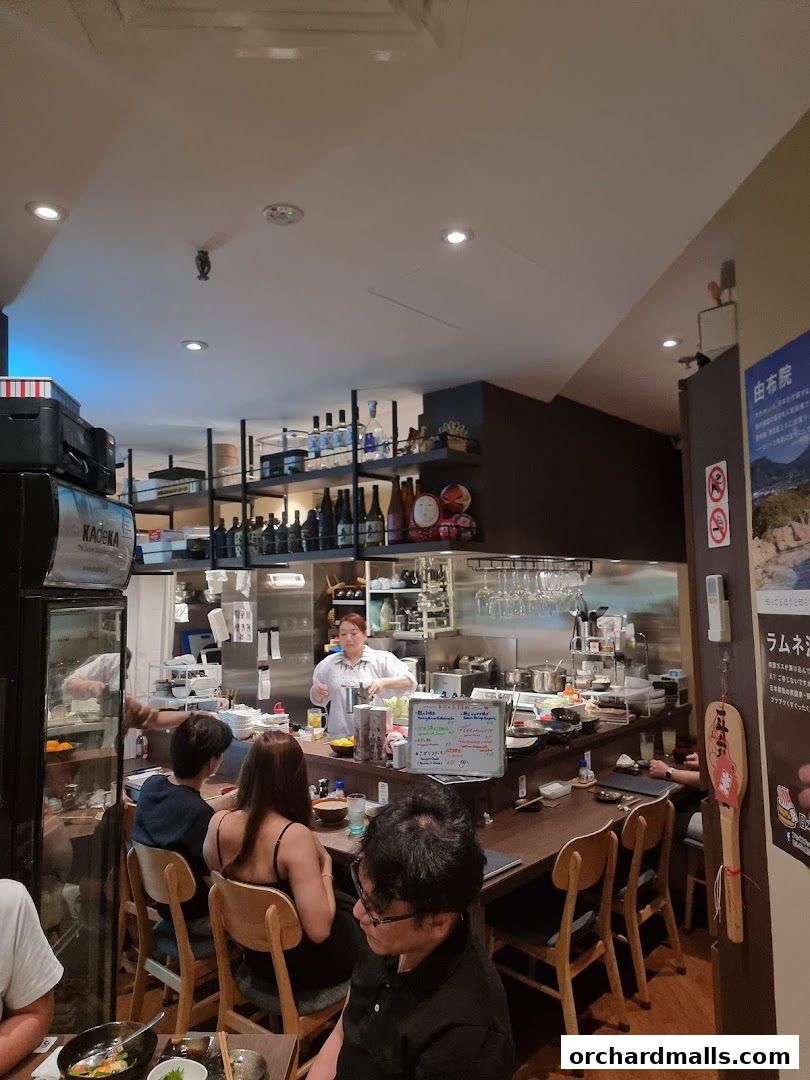 Interior of a Japanese izakaya with diners at the counter and a chef preparing food.