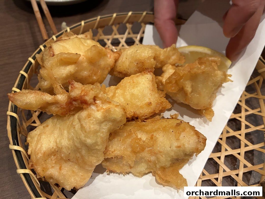 Crispy fried Japanese tempura served in a woven basket with a lemon slice.