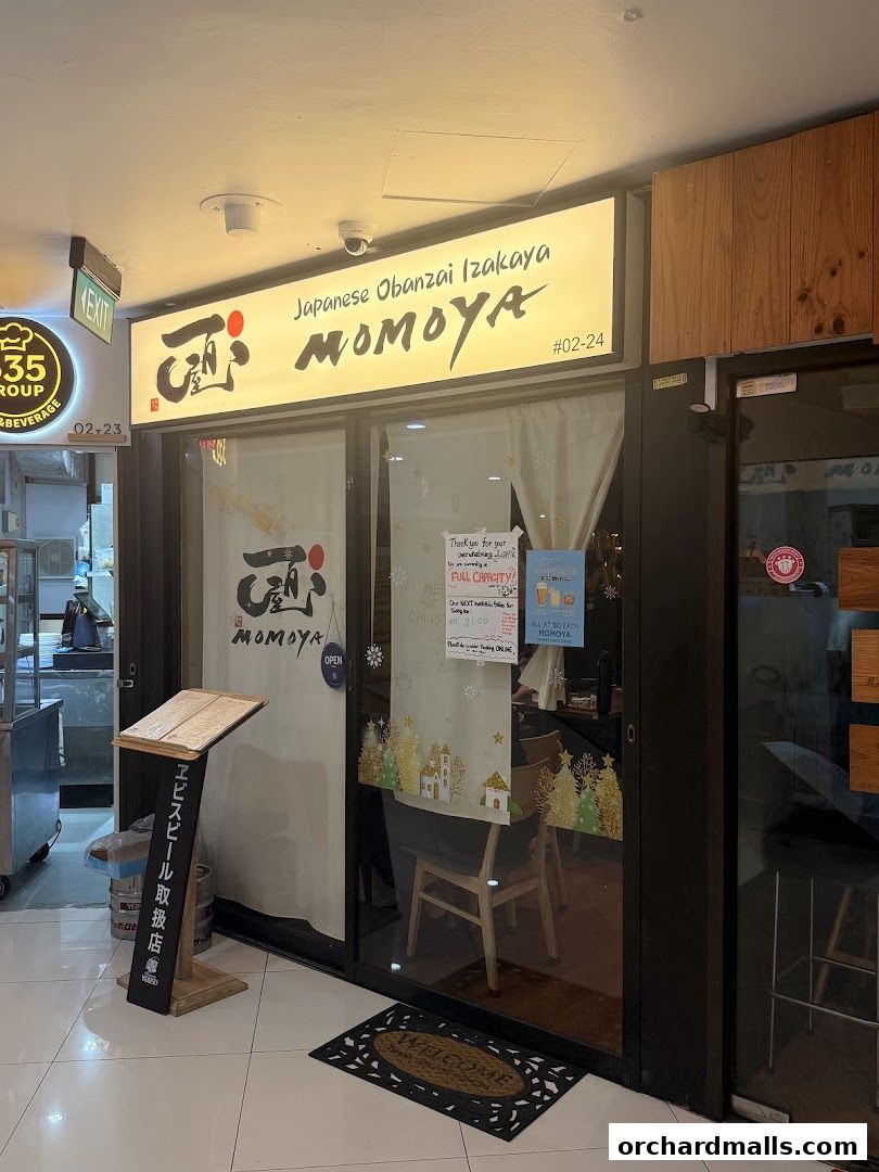 The entrance of MOMOYA, a Japanese Obanzai Izakaya, with its illuminated sign and menu stand.