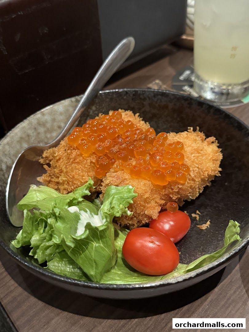 A close-up of a Japanese dish with fried food, salmon roe, lettuce, and cherry tomatoes.