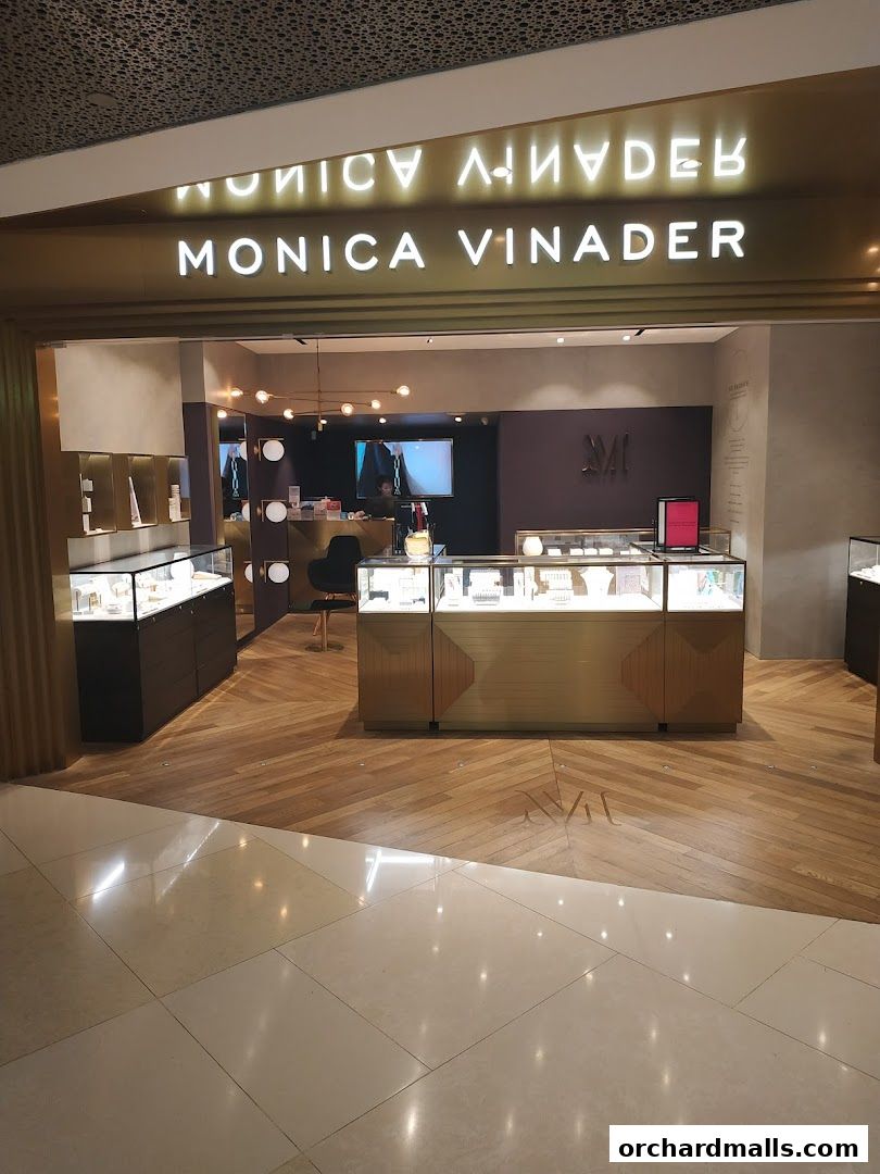 The entrance to a Monica Vinader jewelry store with illuminated signage and display cases.