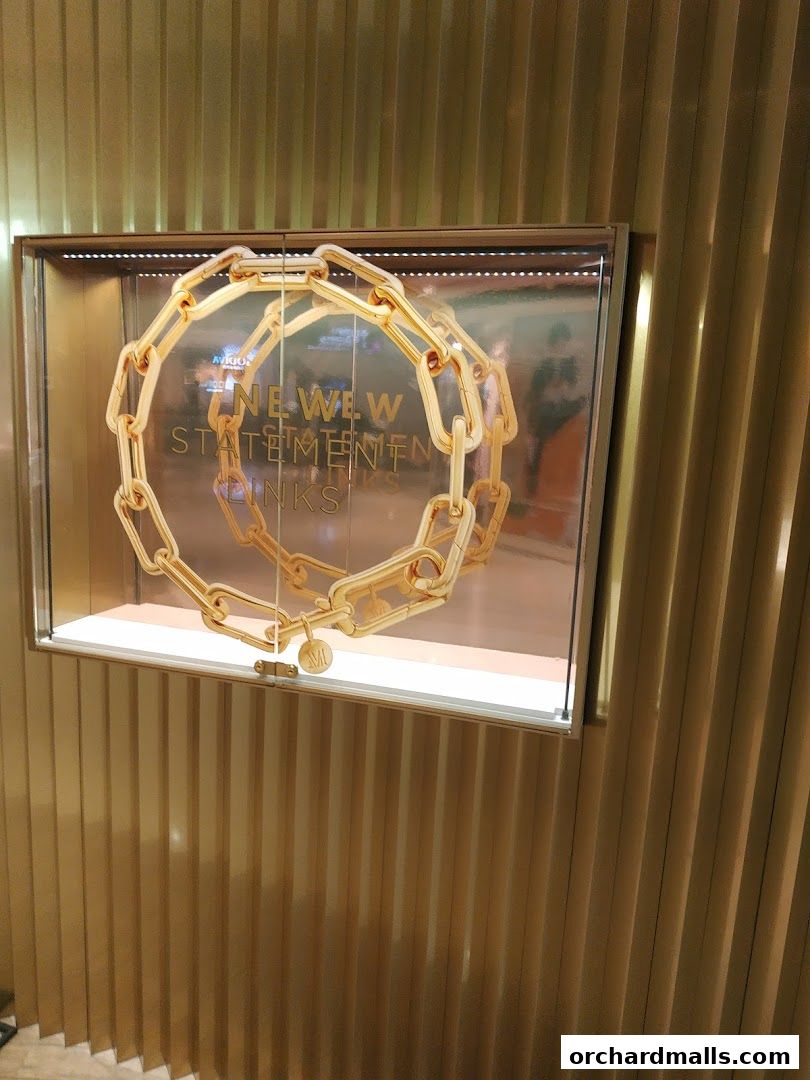A display case showcases a large, chunky gold chain necklace with the text 'NEW STATEMENT LINKS'.