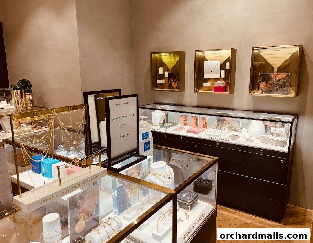 Interior view of a Monica Vinader jewelry store showcasing necklaces, bracelets, and earrings in display cases.