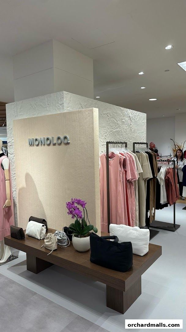 MONOLOQ store interior displaying clothing and handbags on a wooden display table.