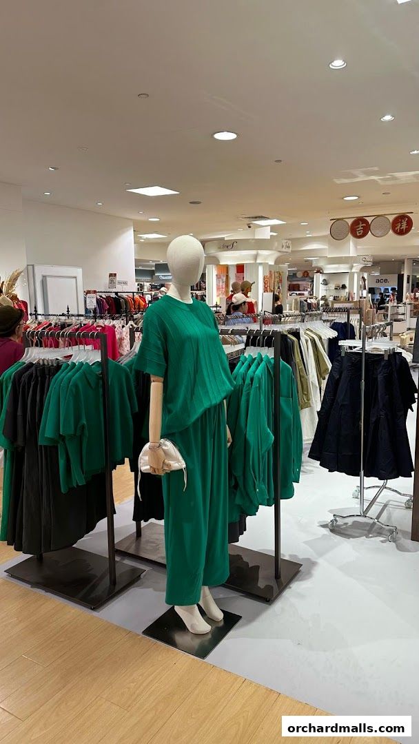 A mannequin displays a stylish green outfit in a clothing store.