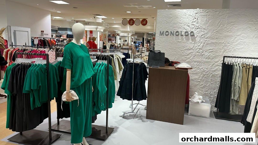 MONOLOQ shop interior displaying racks of green and black clothing, a mannequin, and a textured wall.